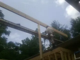 Carpenter setting a ridge beam over a new addition frame — Ice Dam Removal by Roofing Brothers in Mill City