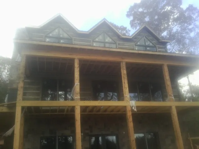 Dormers and porch framing on a large log home under construction — Roof Coating work by our crew in Mill City