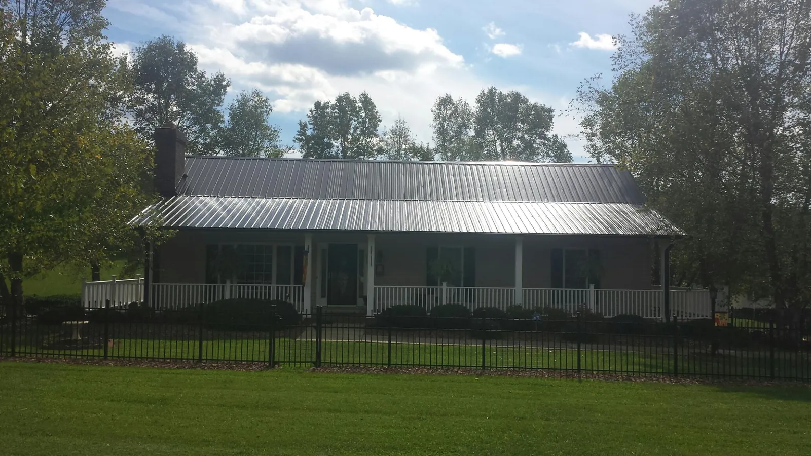 Gray metal roof on a brick ranch with a full width front porch — Gutter Guard Installation work by our crew in Mill City